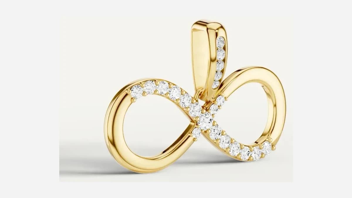 Close photograph of a gold infinity pendant, the pavé along the curve and the stones set into the bail both sharp
