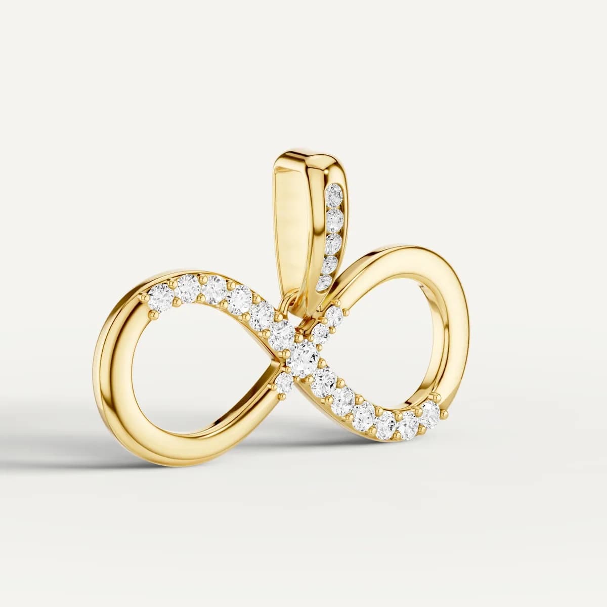 A gold infinity pendant photographed at an angle on a soft off-white background