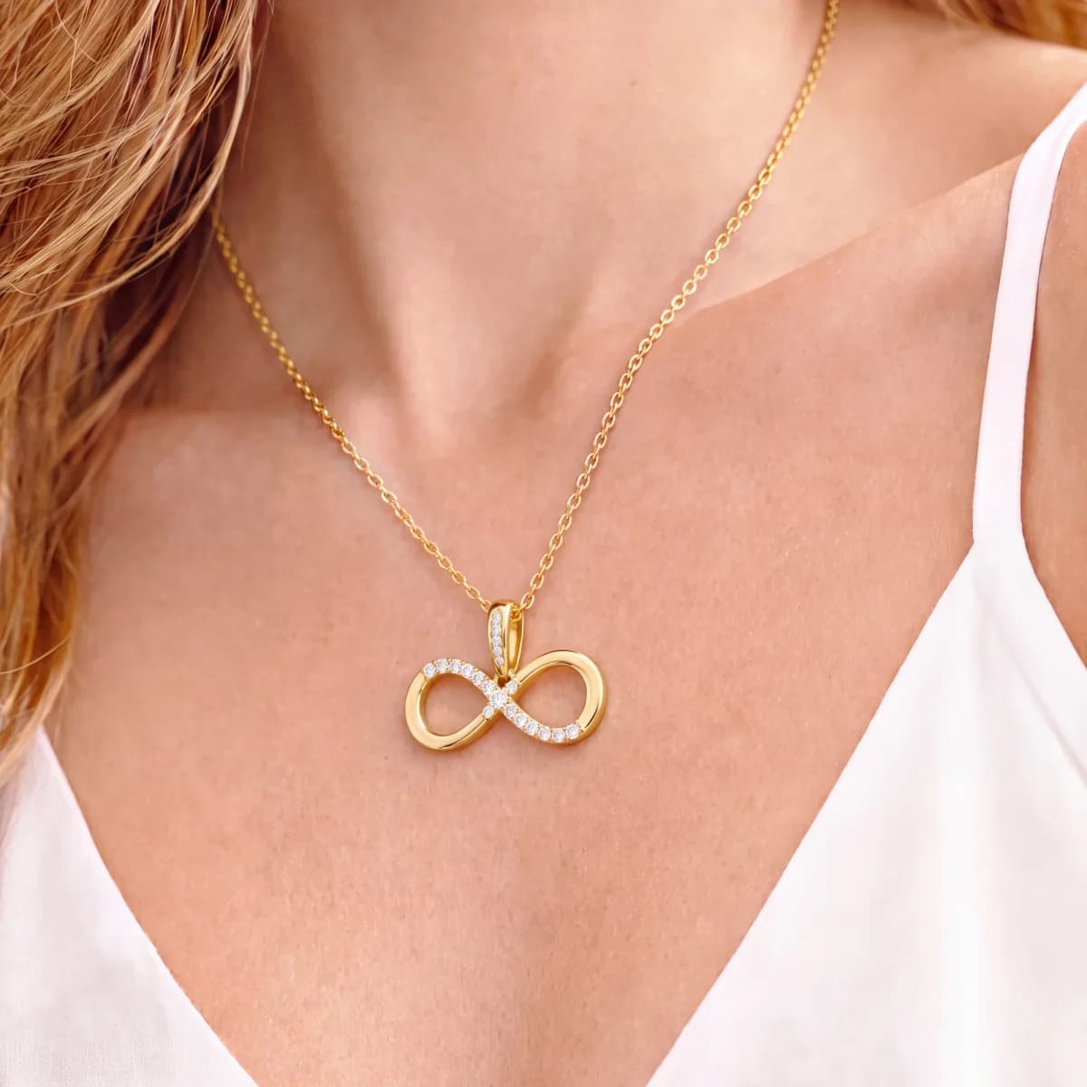 The same infinity pendant worn on a fine gold chain, sitting just below the collarbone