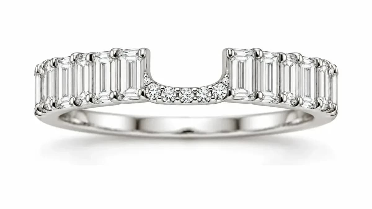 Close photograph of a curved diamond band, the baguettes, the pavé arc between them and the polished shank all in focus